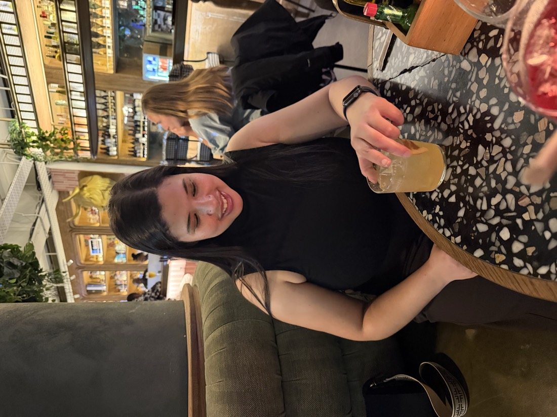 Teneille smiling at a restaurant with a cocktail