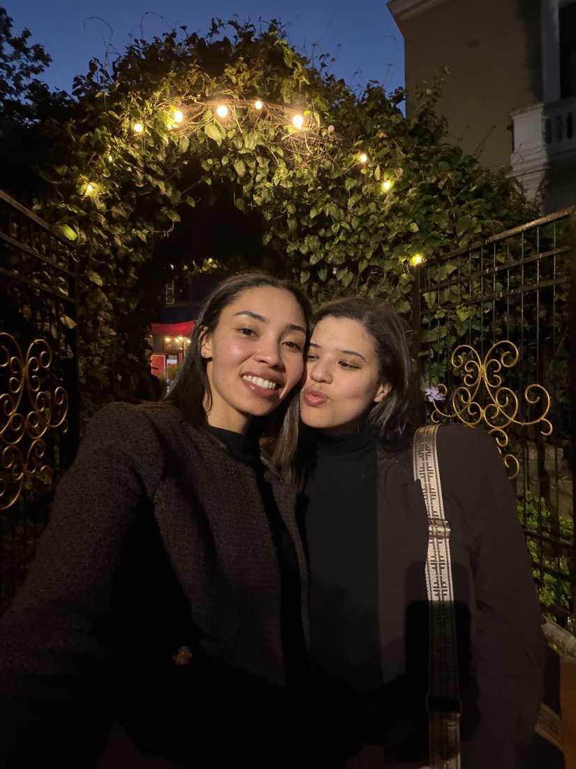 Teneille and Carlynn under a fairy-light arch at night