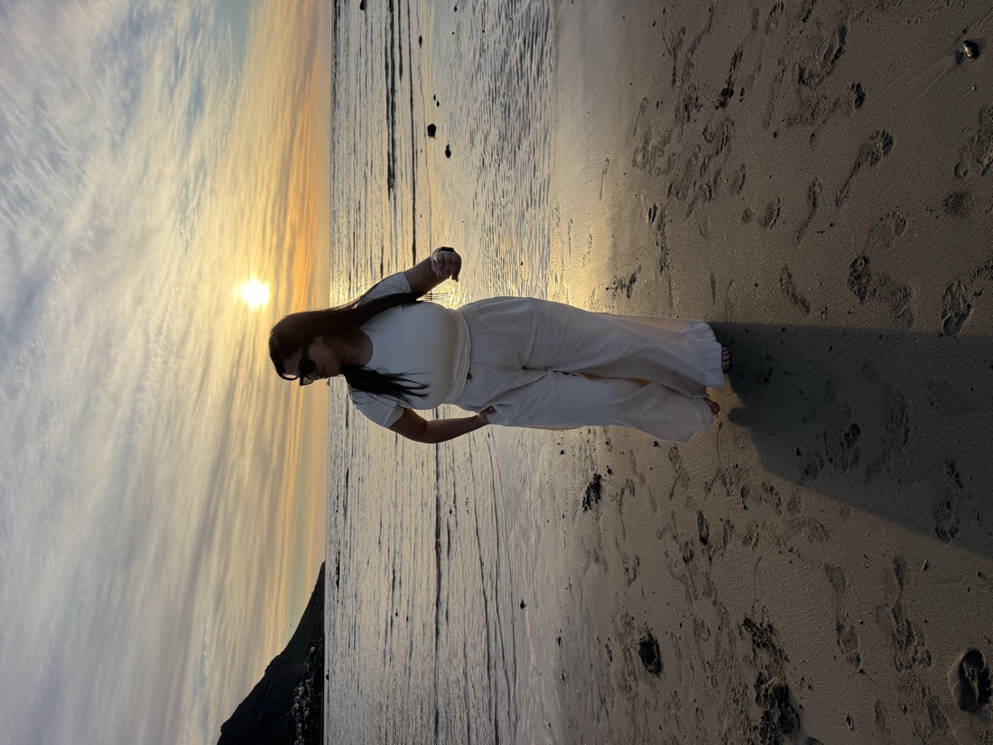 Teneille walking on the beach at sunset in a white outfit