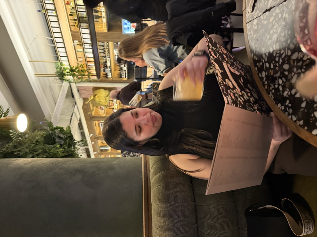 Teneille reading a menu with a drink in hand