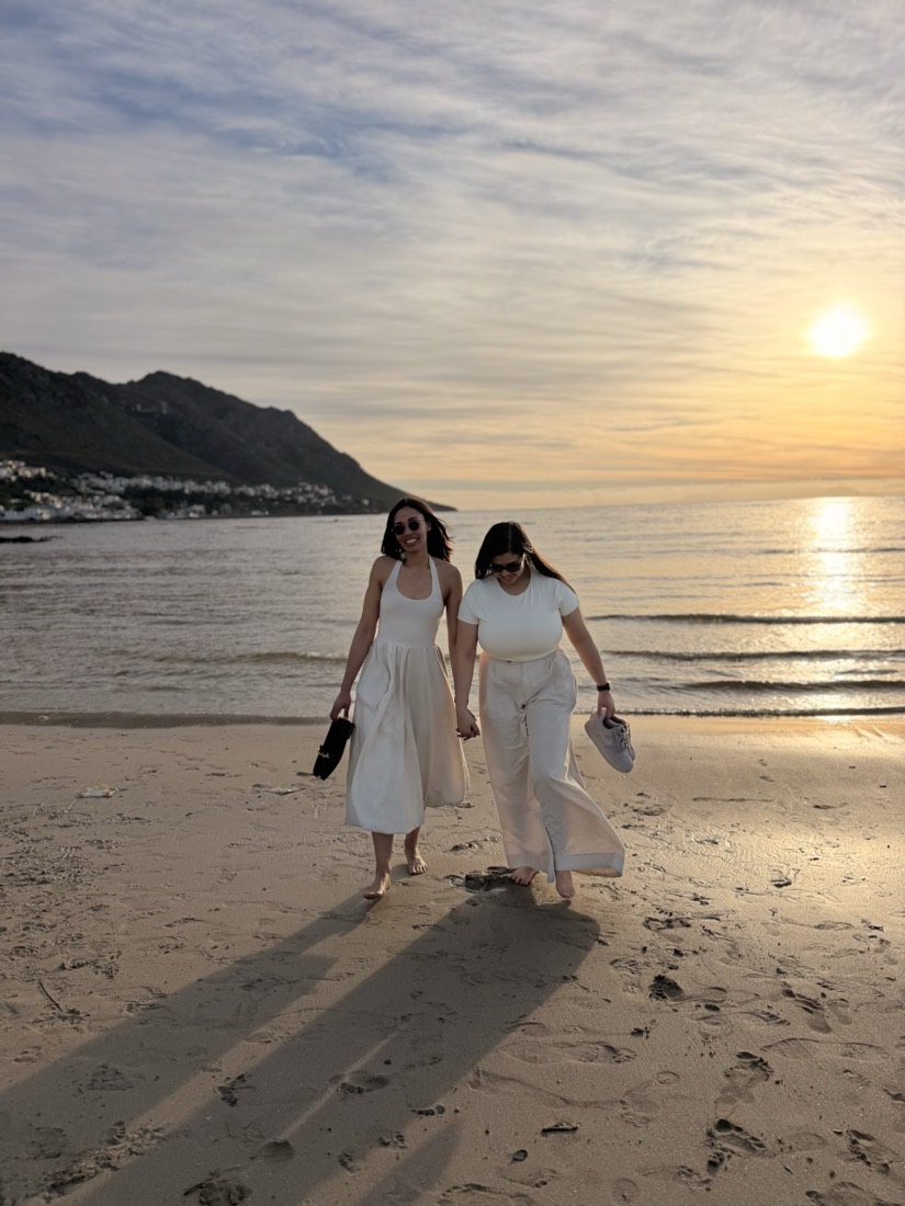 Two people walking along the beach at sunset